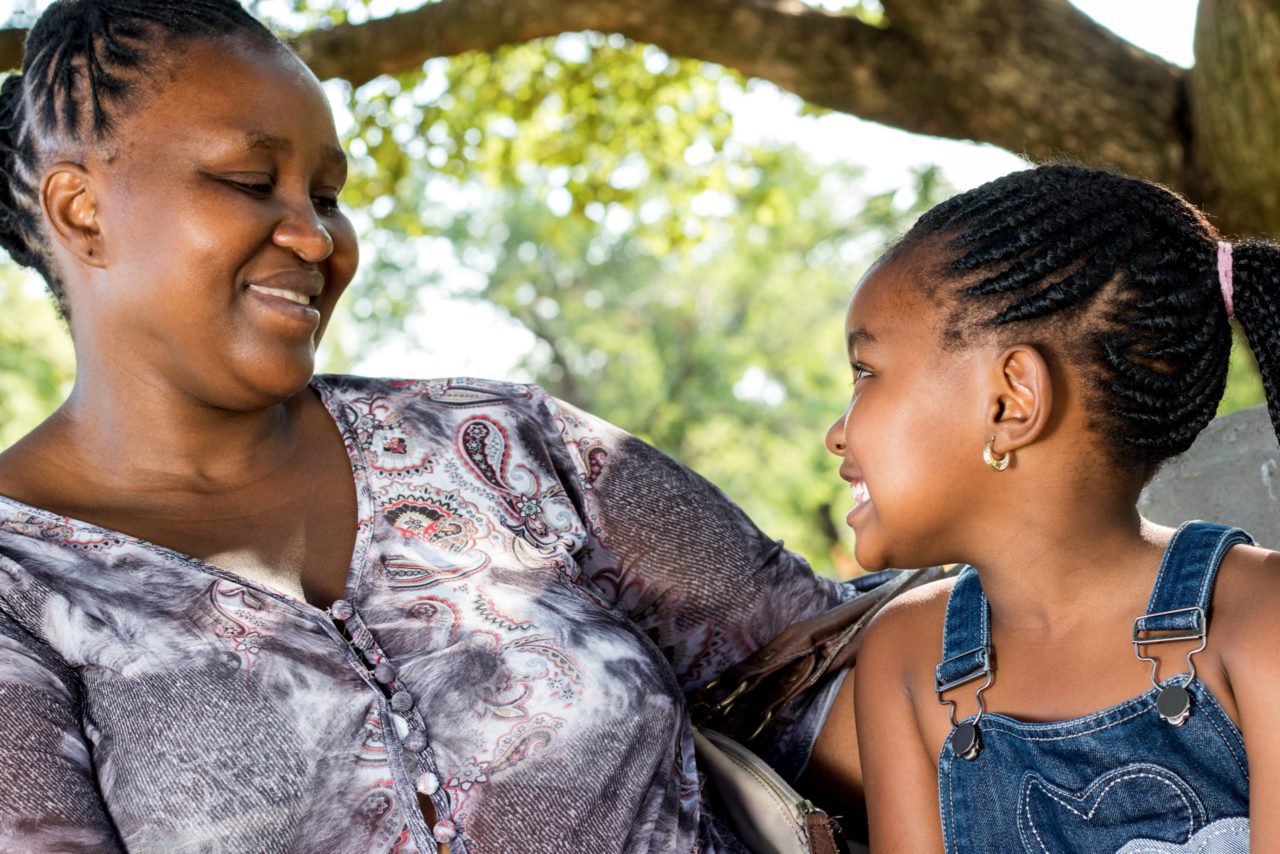 A woman and child smile at each other.