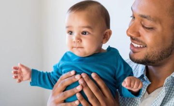 Father holding young baby smiling