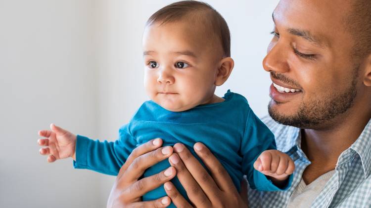 Father holding young baby smiling