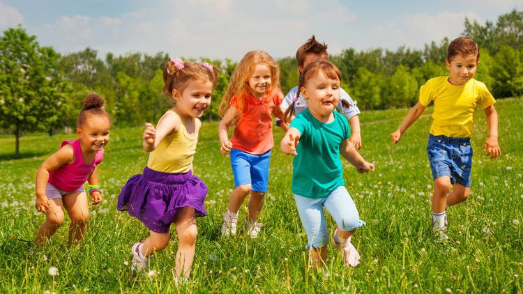 Young toddlers running and laughing in a grass field