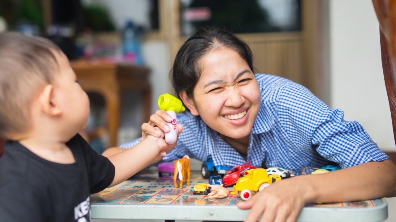 A child holds a toy up to his mother's face.