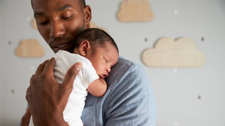 Father holding young baby in their arms