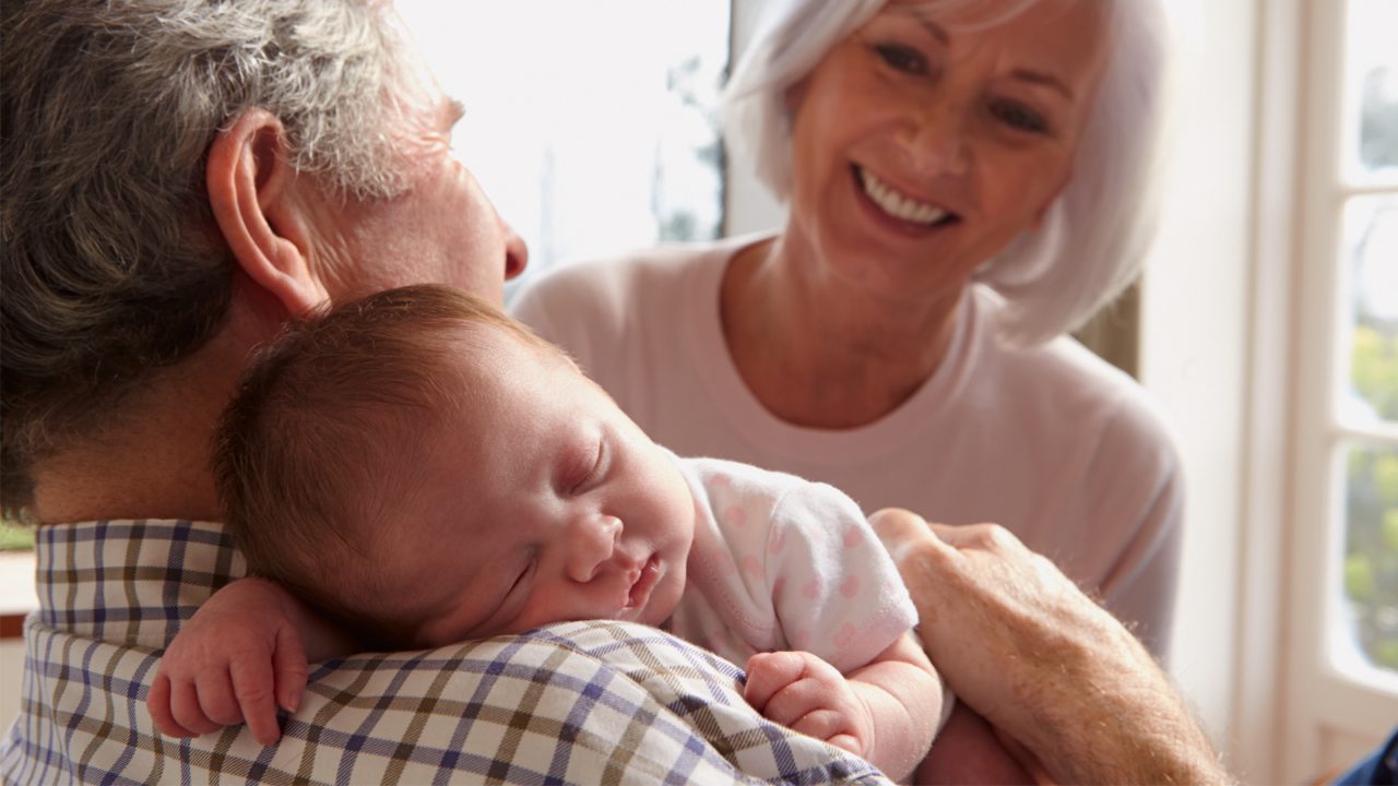 grandparents hold sleeping baby