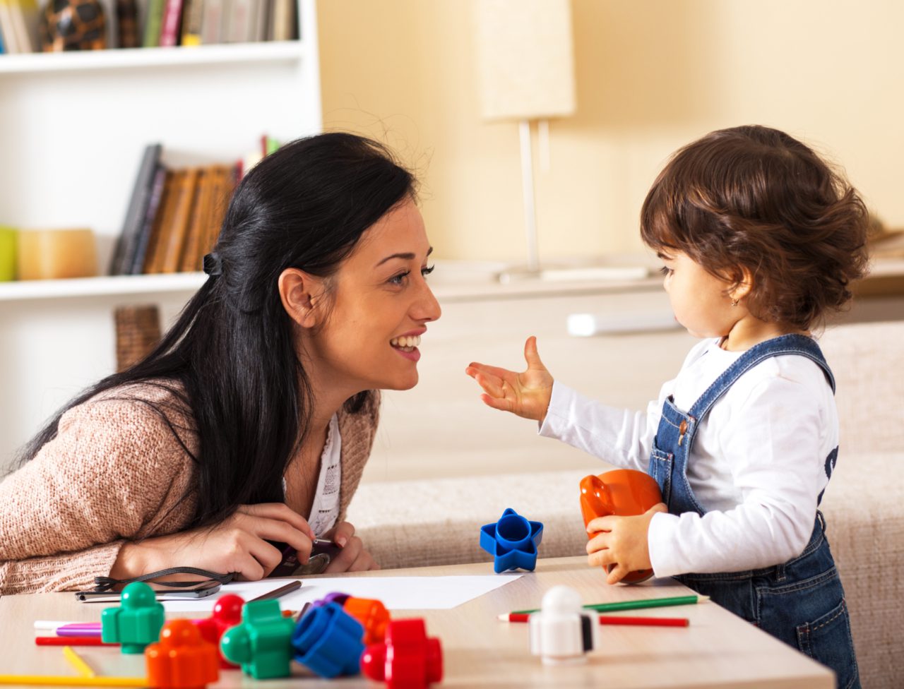 woman watches toddler playing with toys