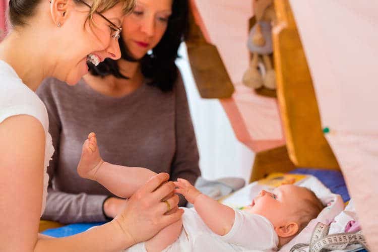 Parent with medical care professional helping a baby