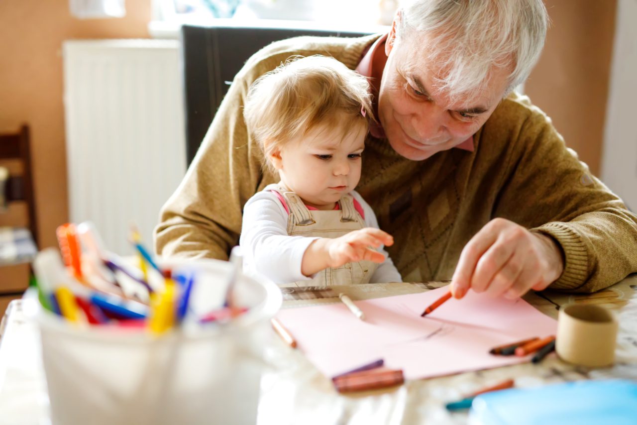 A grandfather colors with his grandchild.