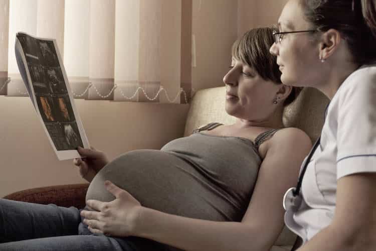 Mother looking at pregnancy exam with doctor