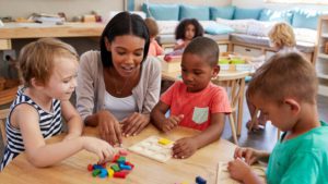 Child care professional sitting down with toddlers