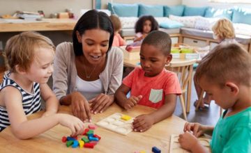 Child care professional sitting down with toddlers