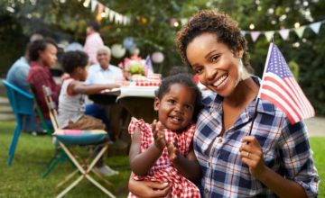 mother holding daughter and american flag