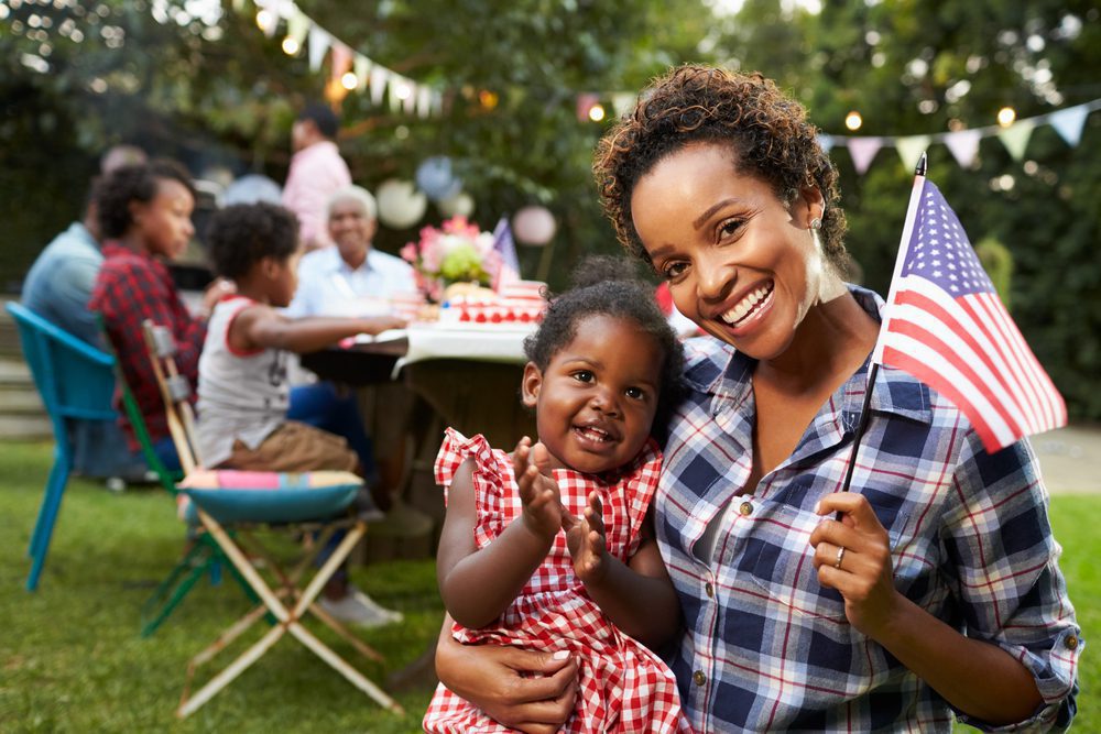 mother holding daughter and american flag