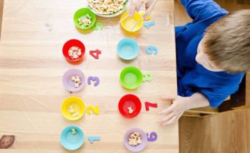 Numbered bowls containing cereal on a table. A child's is arranging the bowls.