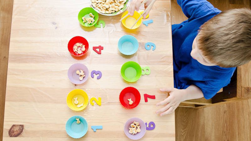Numbered bowls containing cereal on a table. A child's is arranging the bowls.