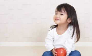 toddler girl holding an apple