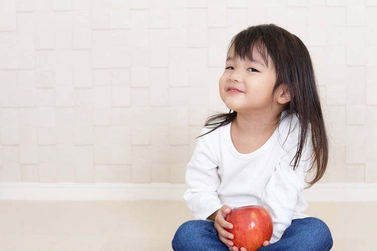 toddler girl holding an apple