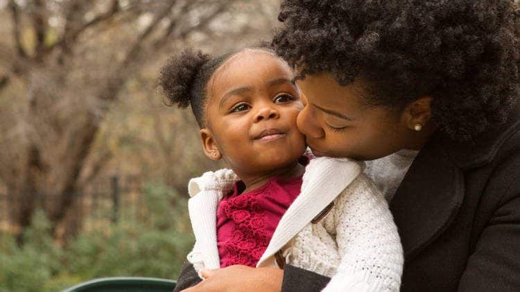 mom kissing toddler girl