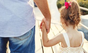 girl and father holding hands walking