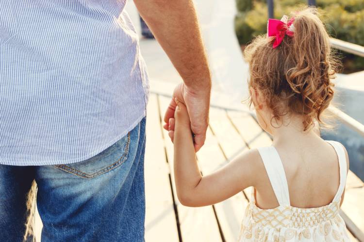 girl and father holding hands walking