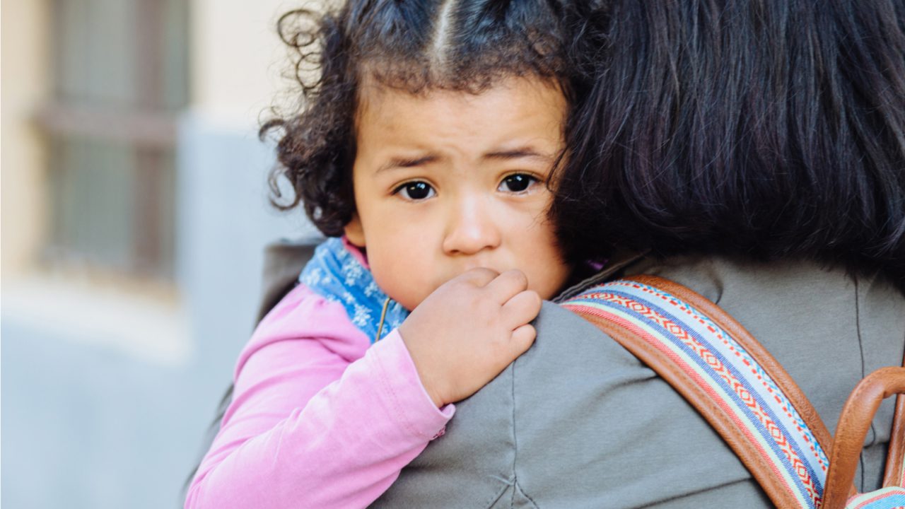 sad child looks over parent shoulder