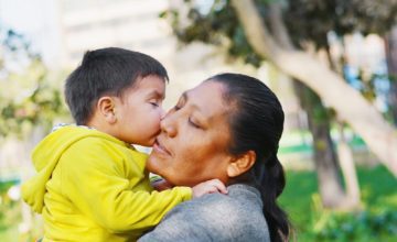 mother holds child giving kiss