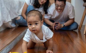 a baby crawling with parents smiling