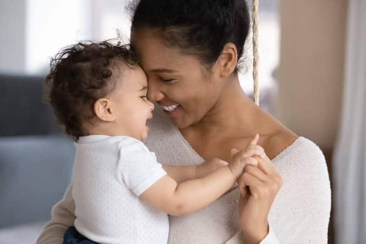 Mother holding infant and smiling together