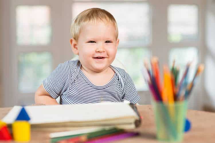 toddler sitting at table with art supplies