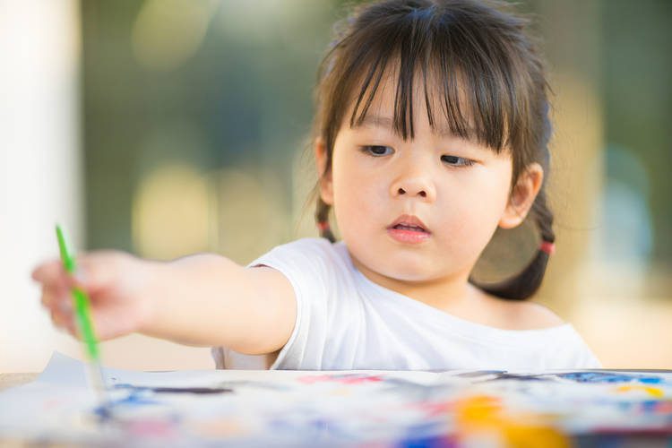 Toddler painting a picture with paint brush