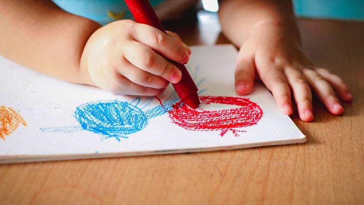 A child coloring a red and blue circle with crayon