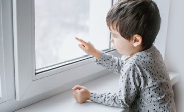 sad toddler looking out window