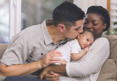Family holding baby; father kissing baby