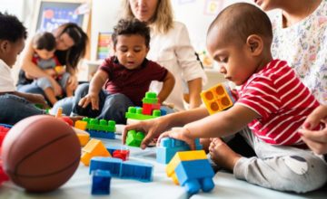 Toddlers playing with toys with caregivers nearby.