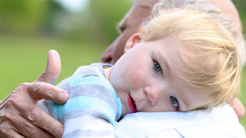 A baby laying his head on a caretaker's shoulder