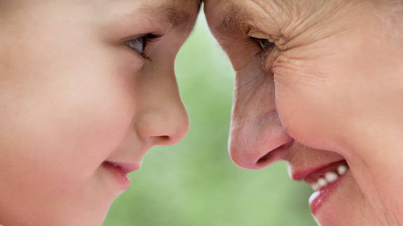 Grandmother and child forehead to forehead looking at each other in the eye.