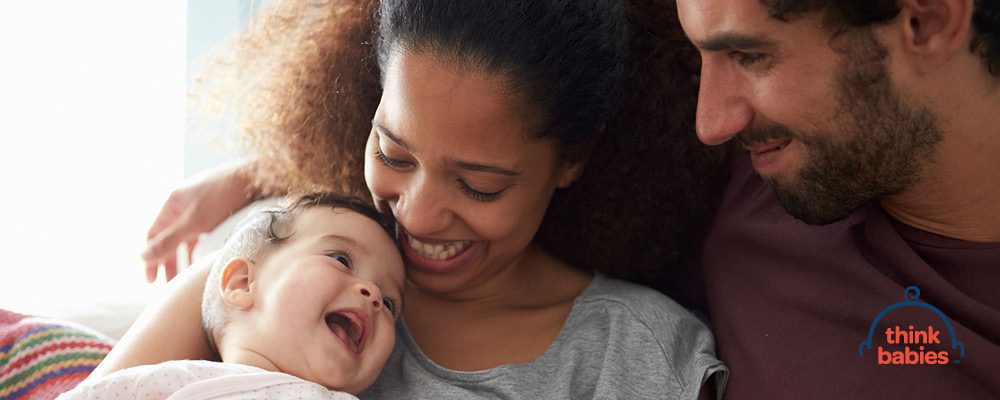 Two adults cuddle a smiling baby