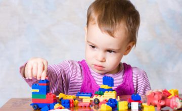 A baby stacks blocks.