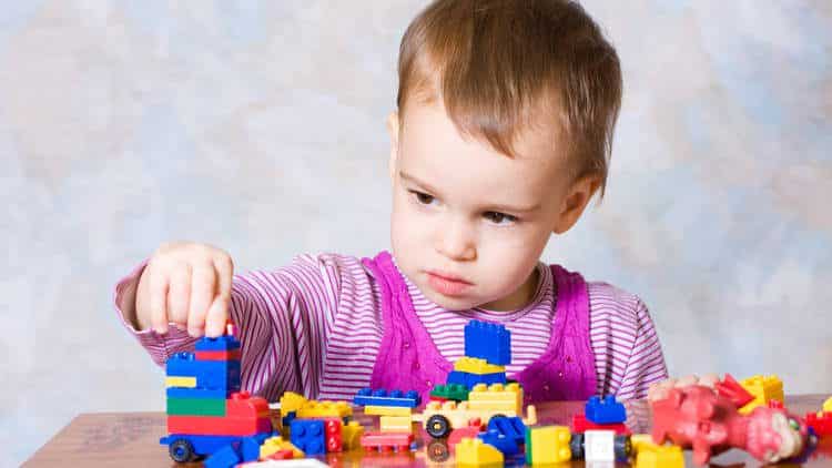 A baby stacks blocks.