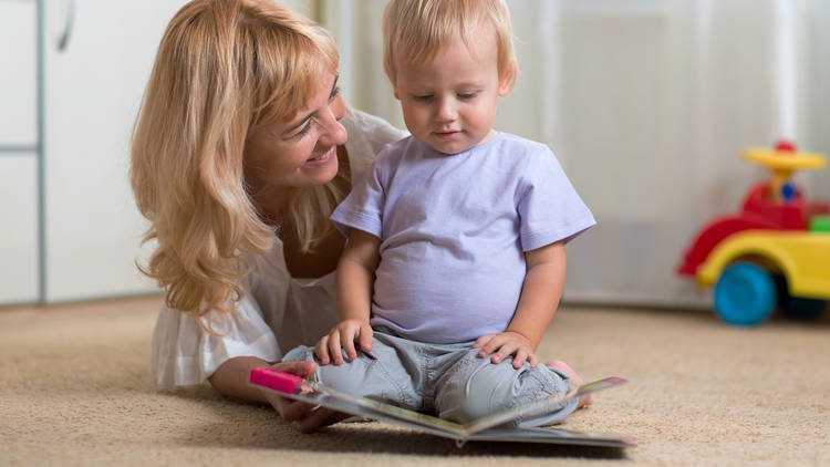 A woman and toddler read a book together. 