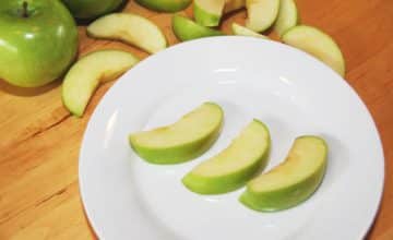 Three slices of green apple on a plate.