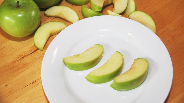 Three slices of green apple on a plate.