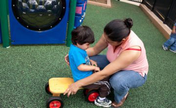An early childhood educator squatting down to talk to a sad child