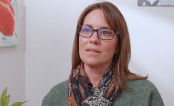 a woman with brown hair and glasses talking to the camera