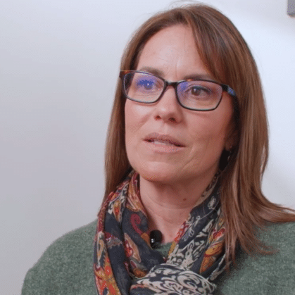 a woman with brown hair and glasses talking to the camera