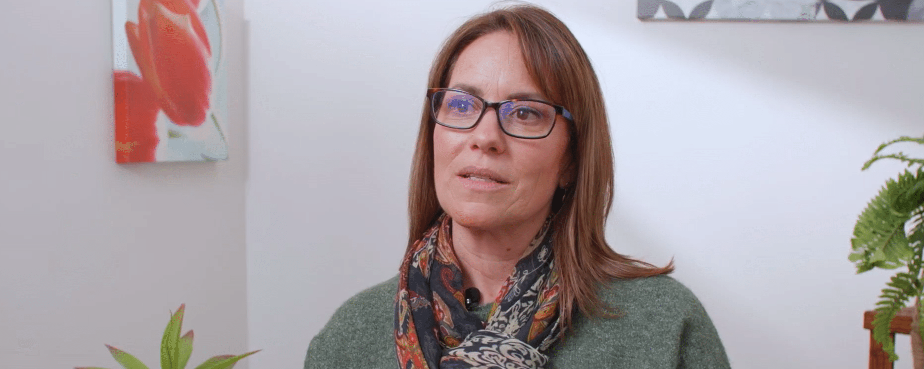 a woman with brown hair and glasses talking to the camera