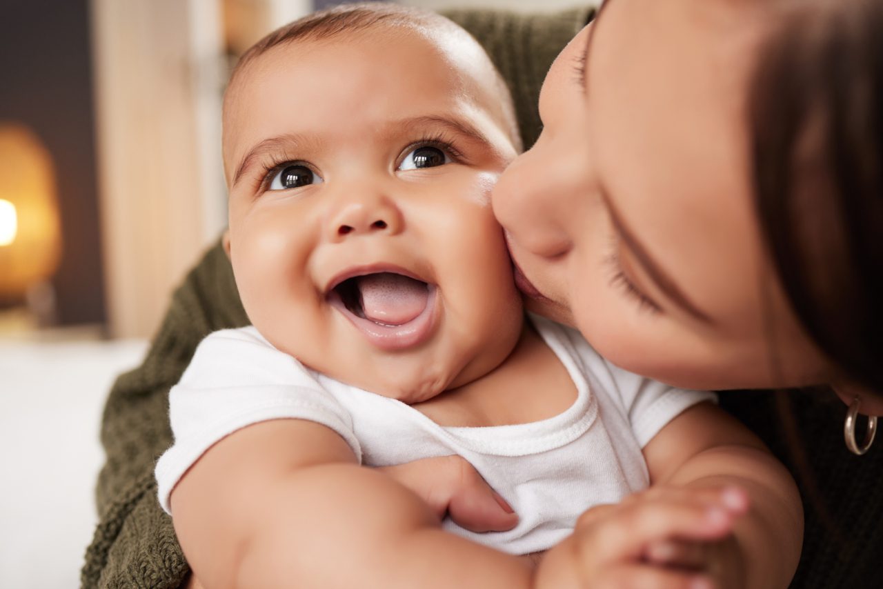 Mom kisses baby on the cheek.