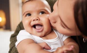 Mom kisses baby on the cheek.