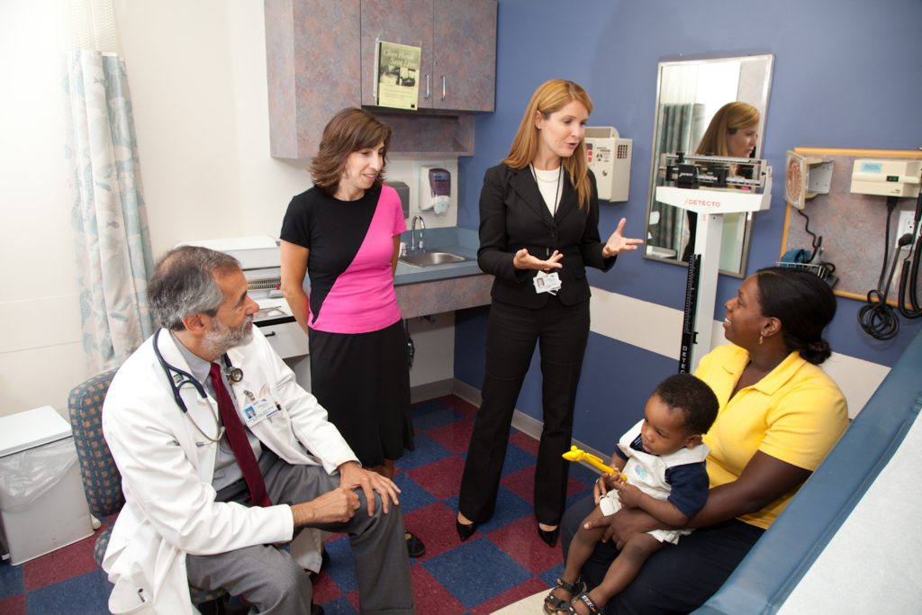 Healthy Steps specialist and pediatrician talking to a mother holding her toddler