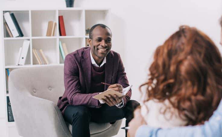 Smiling african american psychiatrist talking to young couple