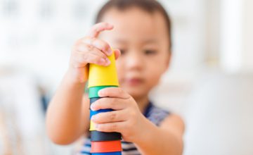 Little asian toddler boy playing stacking cups learning materials in a montessori methodology school being manipulated by children.Montessori classroom for the learning of children in mathematics.
