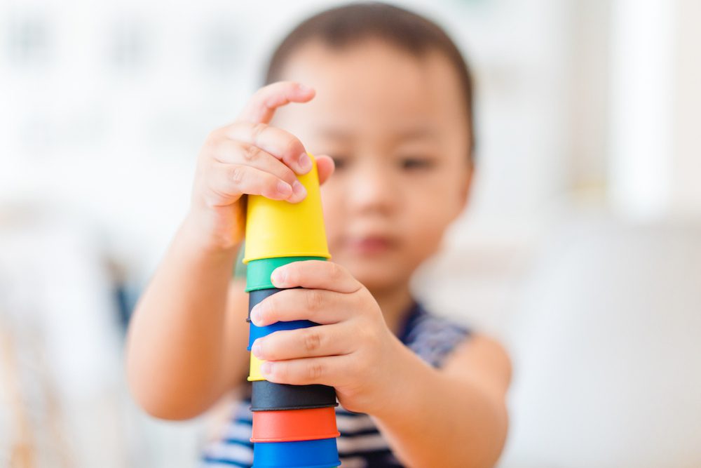 Little asian toddler boy playing stacking cups learning materials in a montessori methodology school being manipulated by children.Montessori classroom for the learning of children in mathematics.